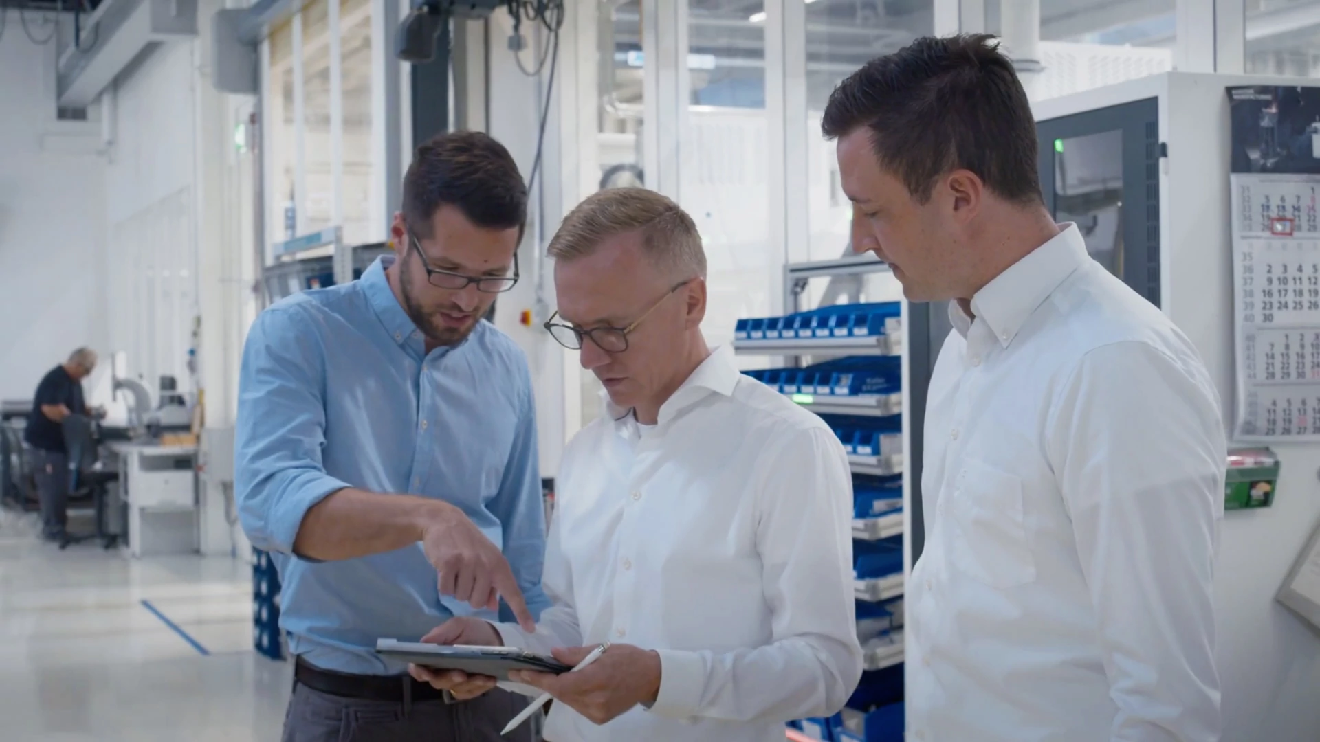 3 Betriebsleiter diskutieren gemeinsam die auf einem Tablet dargestellten Daten.